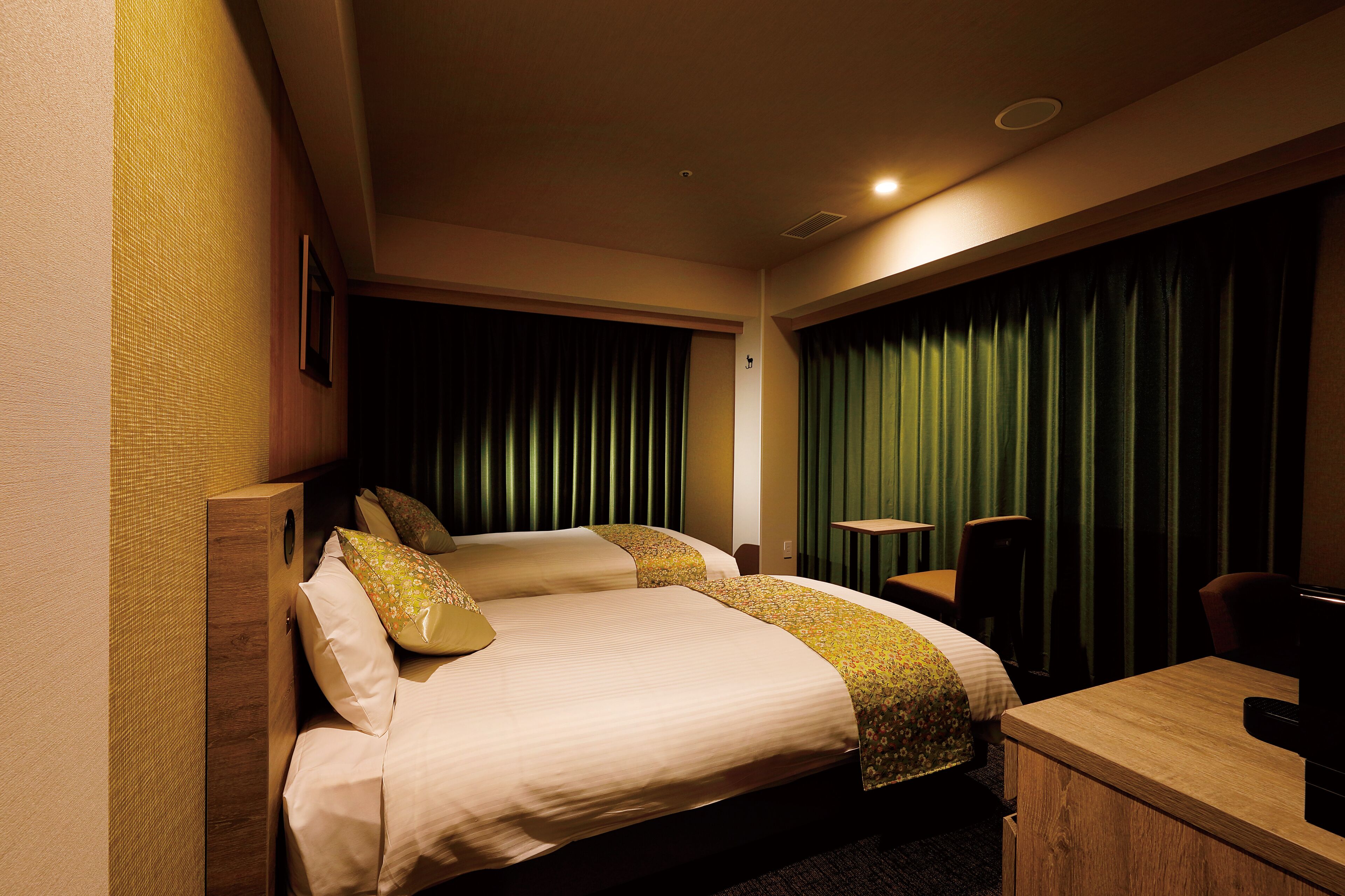 A hotel room with two beds, a desk, and a chair.