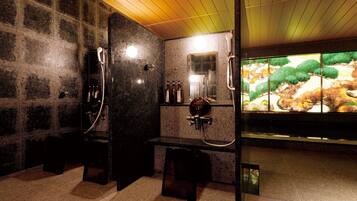 A modern bathroom with a stone wall, a bench, a mirror, and a large window with a view of trees and rocks.