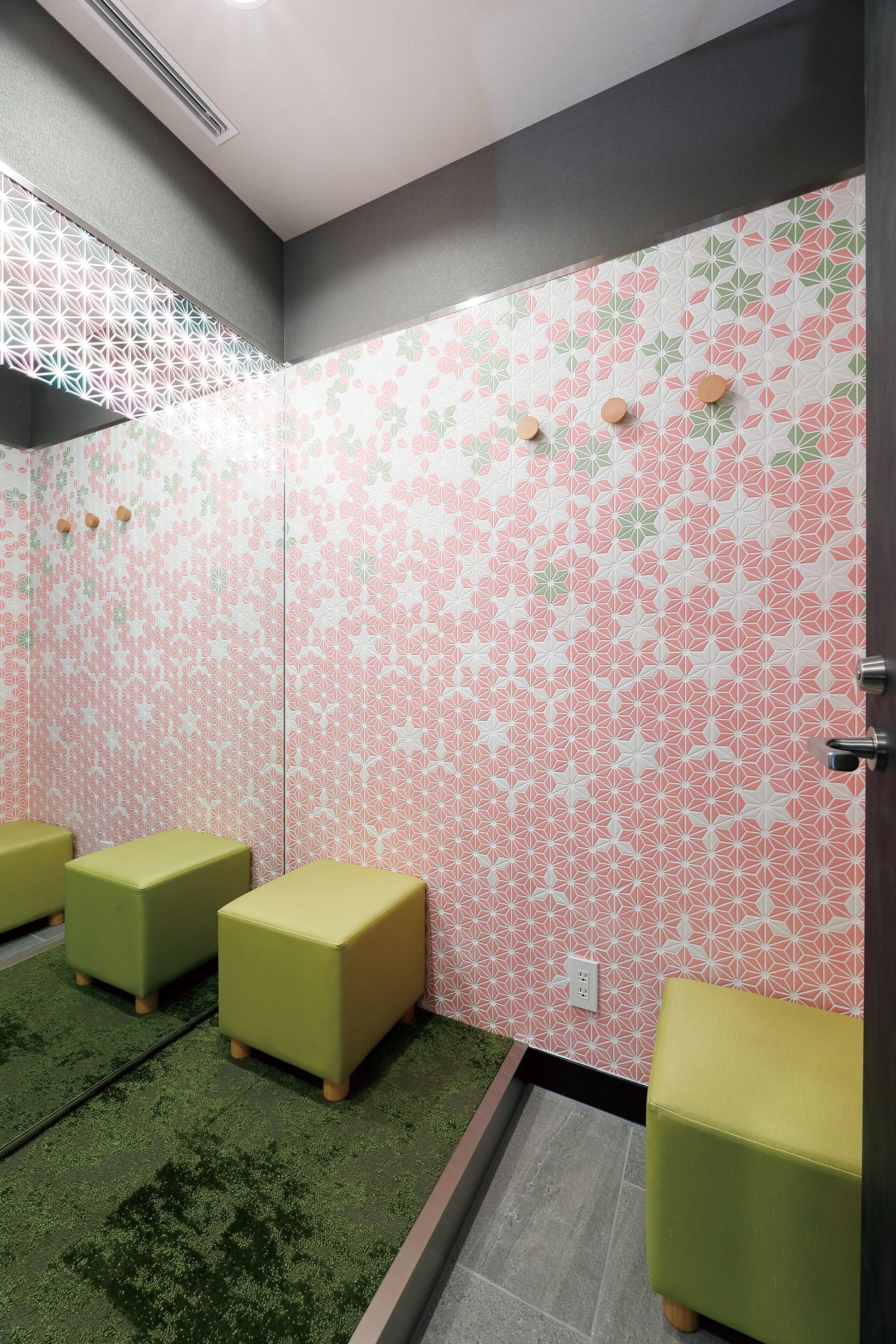 Eine Toilette mit grün gepolsterten Bänken, einem Spiegel und einer Wand mit Muster.