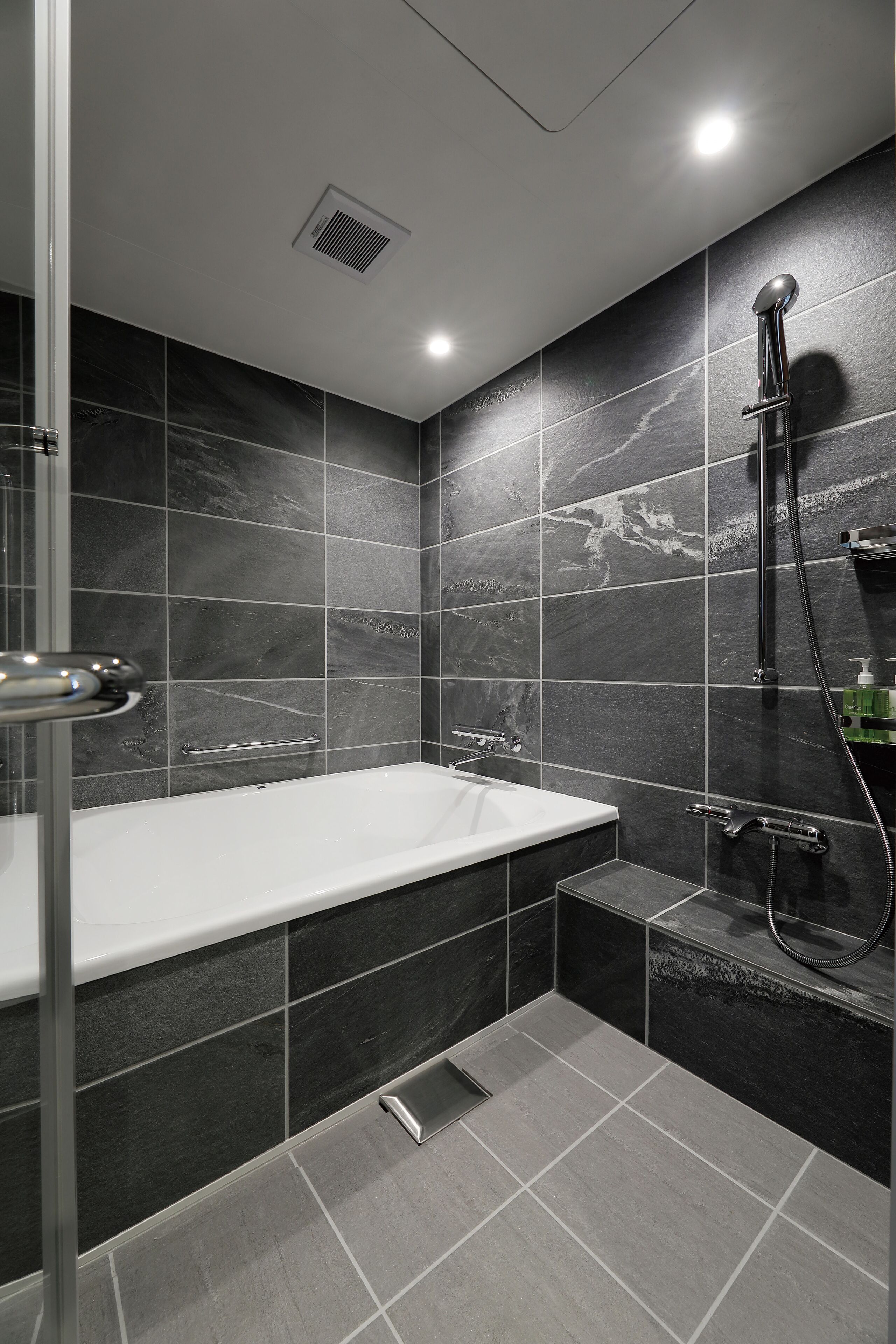 A modern bathroom with a bathtub, shower, and a small vanity area.