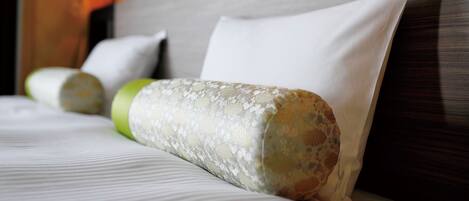 A neatly made bed with a pillow and a rolled-up blanket.