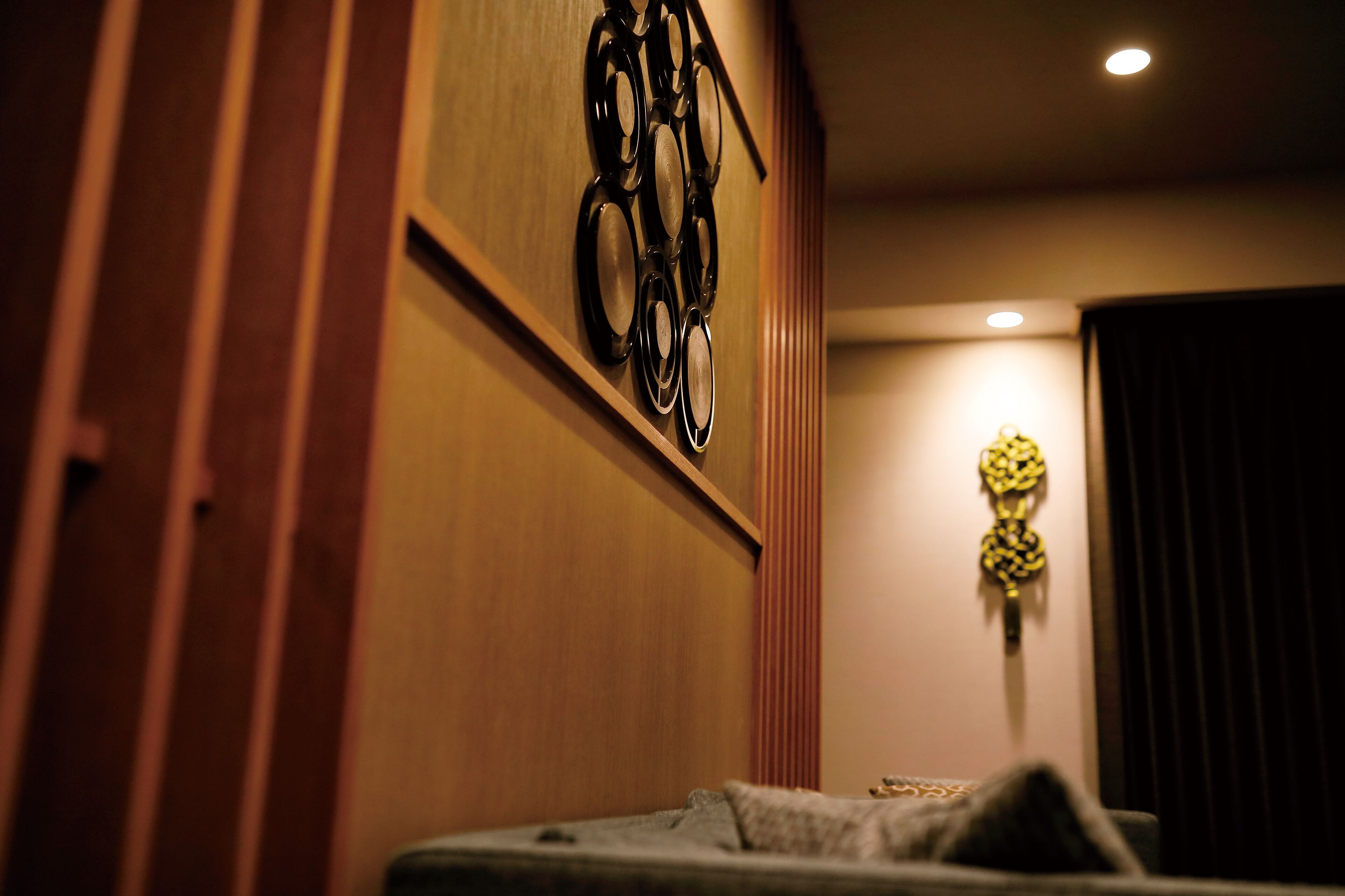 A room with a bed, a wall-mounted circular object, and a decorative item on the wall.