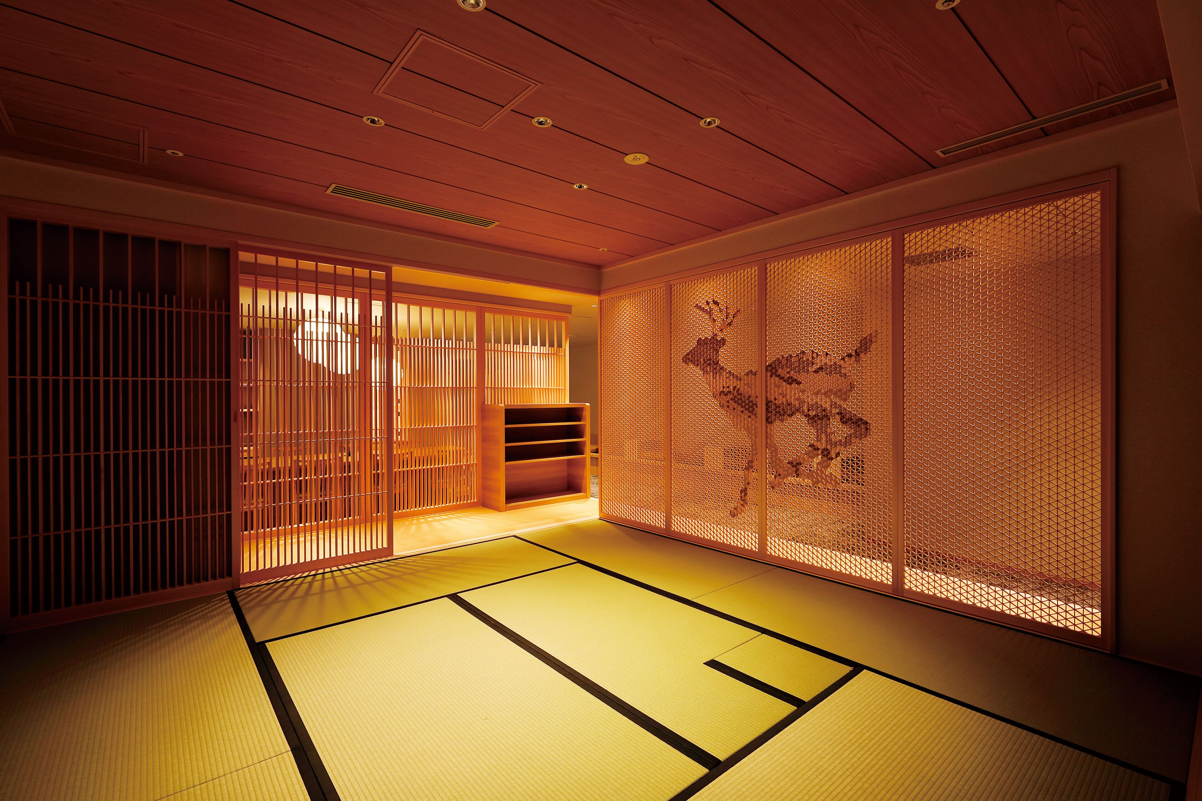 A traditional Japanese room with tatami flooring, sliding doors, and a wooden ceiling.