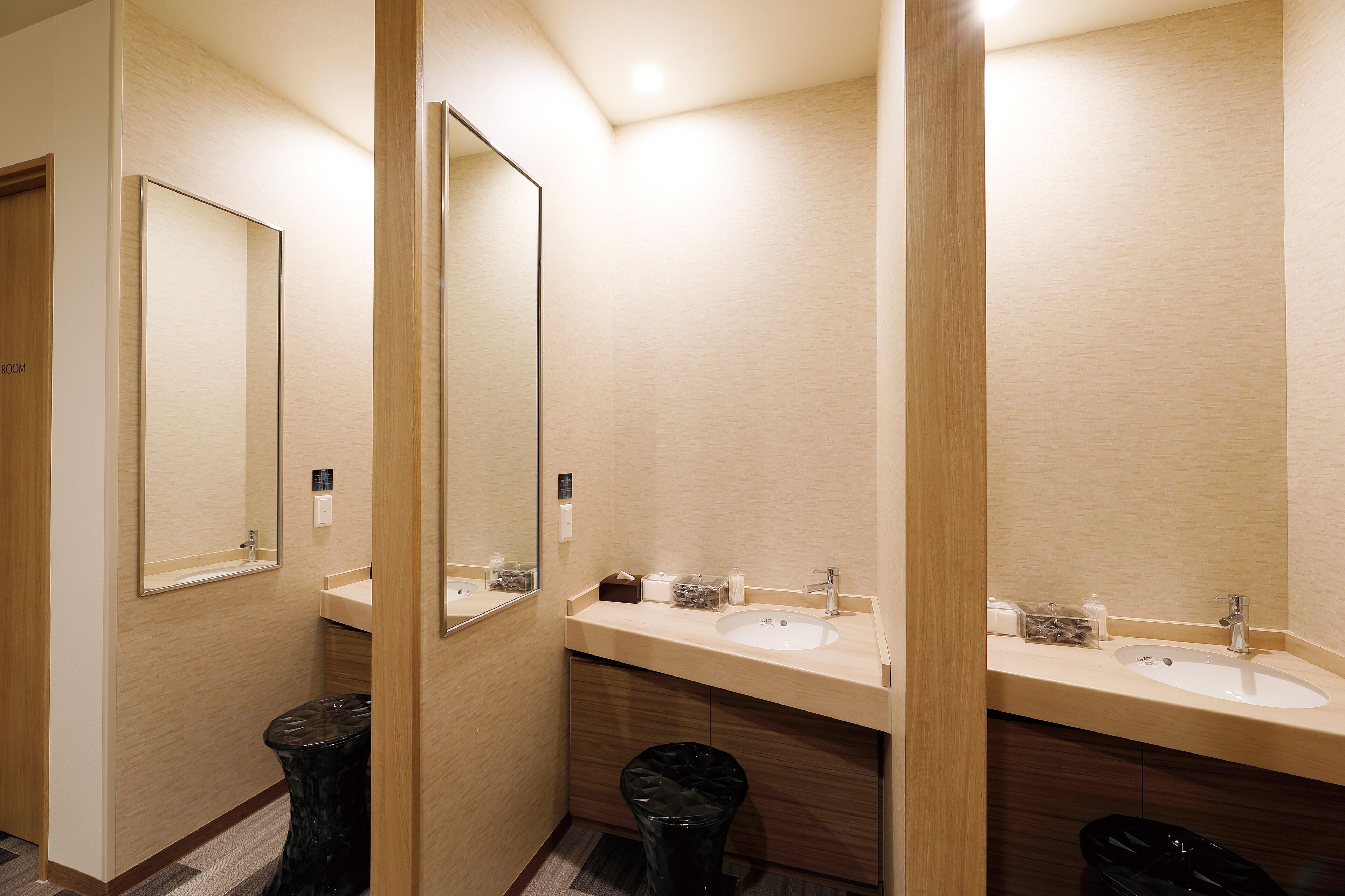 A modern bathroom with two sinks, a mirror, and a trash bin.