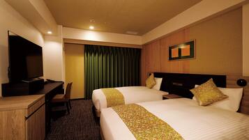 A hotel room with two beds, a desk, a television, and a green curtain.