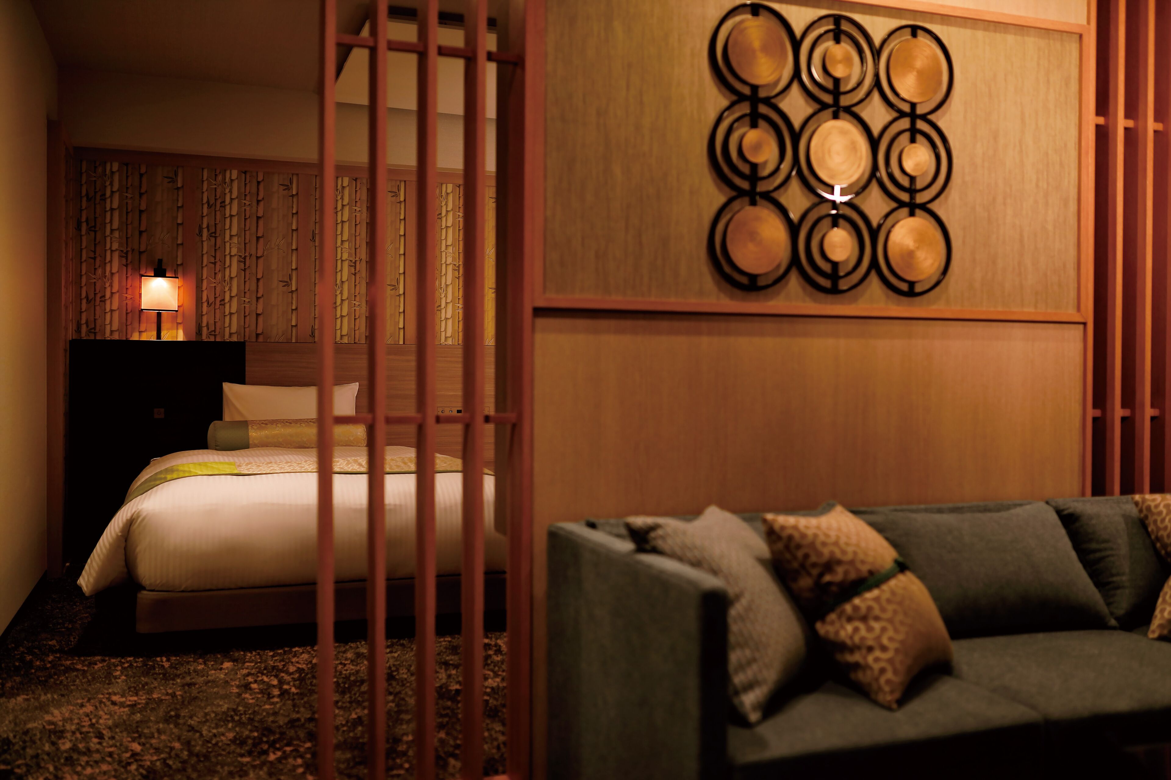 Ein Hotelzimmer mit einem Bett, einem Holzkopfbrett, einer wandmontierten runden Dekoration und einem grünen Sofa.