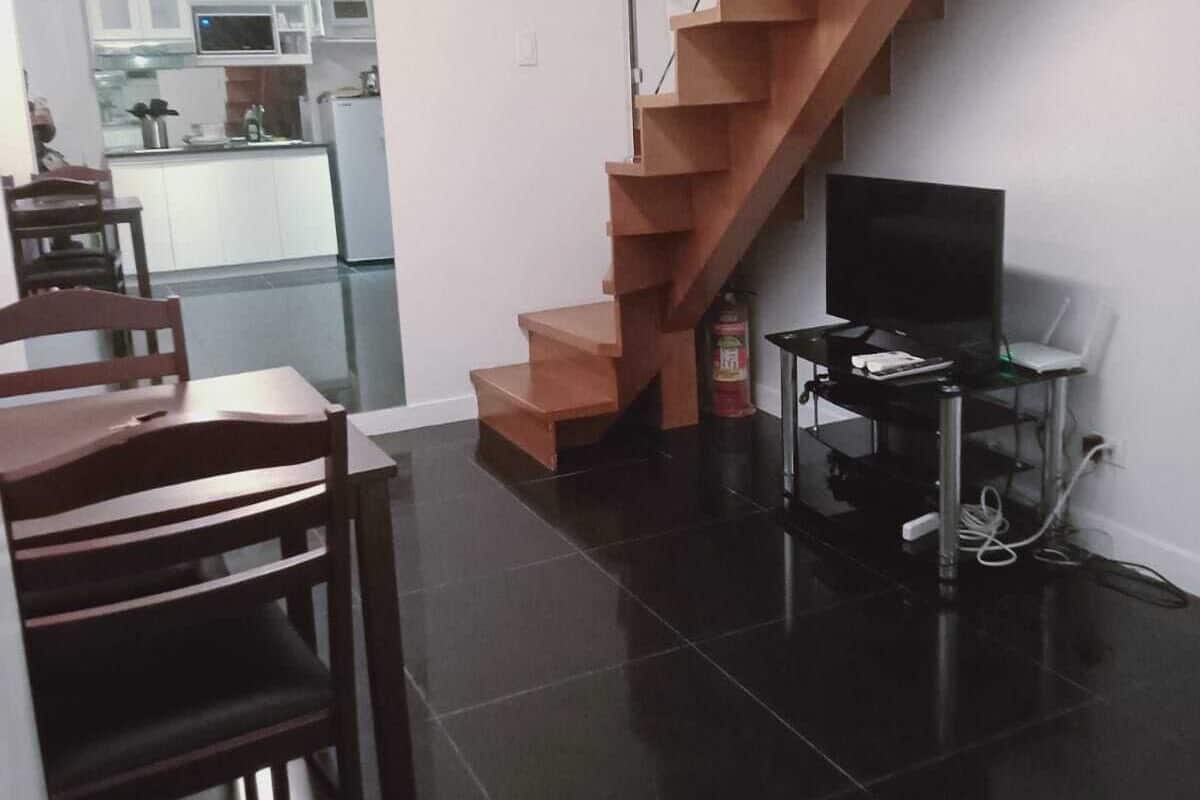 Ein moderner Wohnraum mit Treppe, einem Essbereich und einer Küche im Hintergrund.