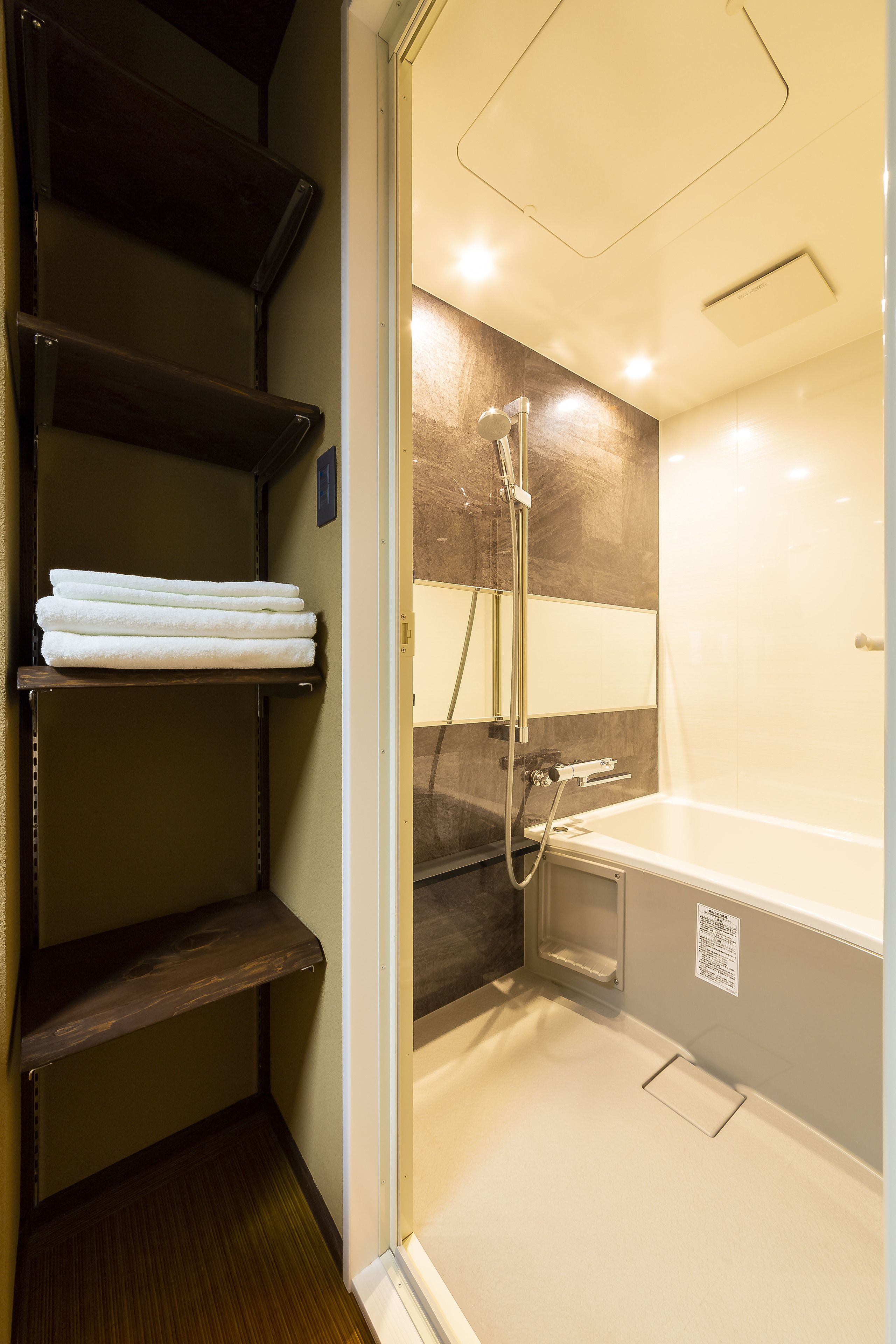 Une salle de bain équipée d’une douche, d’une baignoire et d’une étagère où sont pliées les serviettes.