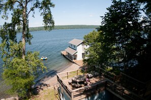 A lakeside cabin with a dock, a small boat, and a deck area with outdoor furniture. - 120 Feet of Private Beachfront (Trumansburg)