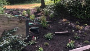 Un jardín con cerca de madera, jardineras elevadas y diversas plantas.