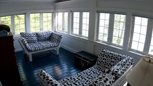 Una habitación con un amplio ventanal, un sofá estampado de lunares, una mesita pequeña y una lámpara.