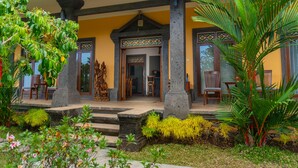 A traditional building with a covered porch, stone columns, and a wooden door with intricate designs.