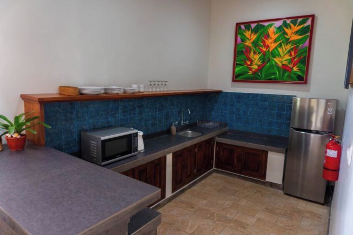 A compact kitchen with a microwave, sink, and stainless steel refrigerator.