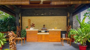 A reception desk with a wooden counter and a receptionist. There are potted plants and a large map on the wall behind the desk.