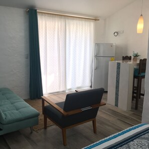 Cozy living space with a sofa, table, and kitchenette area.