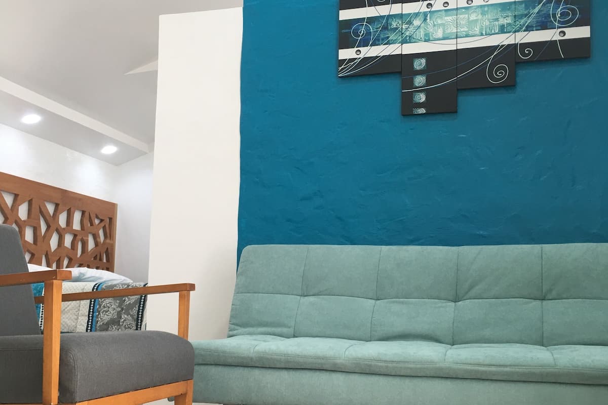 Una sala de estar moderna con un sofá verde claro, una silla de madera y un adorno de pared decorativo.