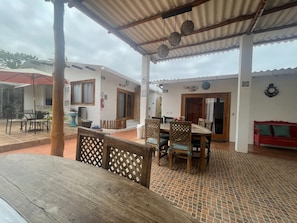 Relax in the CAURA area, surrounded by potted plants and comfortable seating under a covered roof.