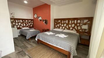 A hotel room with two beds, a wooden headboard, a small table, and a mirror on the wall.