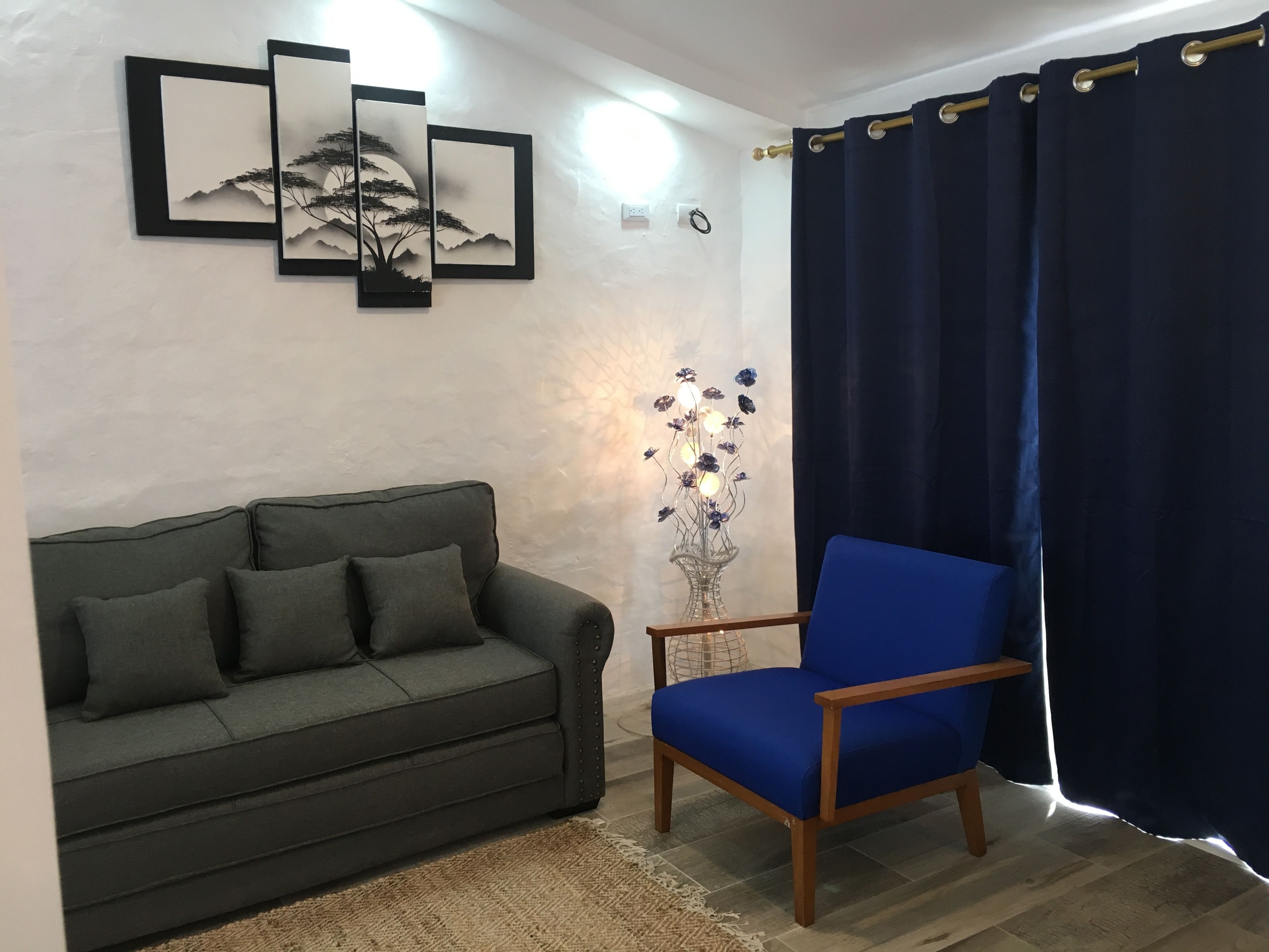 A living room with a dark green sofa, a blue armchair, and a decorative vase with flowers.