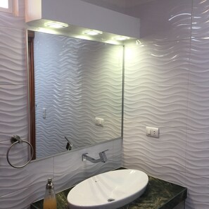 Bathroom features a wavy-patterned tile design, a large mirror, and a white sink with a single faucet.