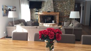 Una sala de estar con chimenea de piedra, televisor de pantalla plana y comedor con mesa y sillas.