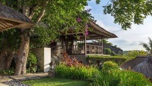 Un edificio de estilo tradicional con techo de paja, rodeado de abundante vegetación y un jardín cuidado.