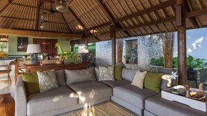 Un amplio espacio de sala con un sofá seccional grande, una mesa de comedor y una zona de cocina.