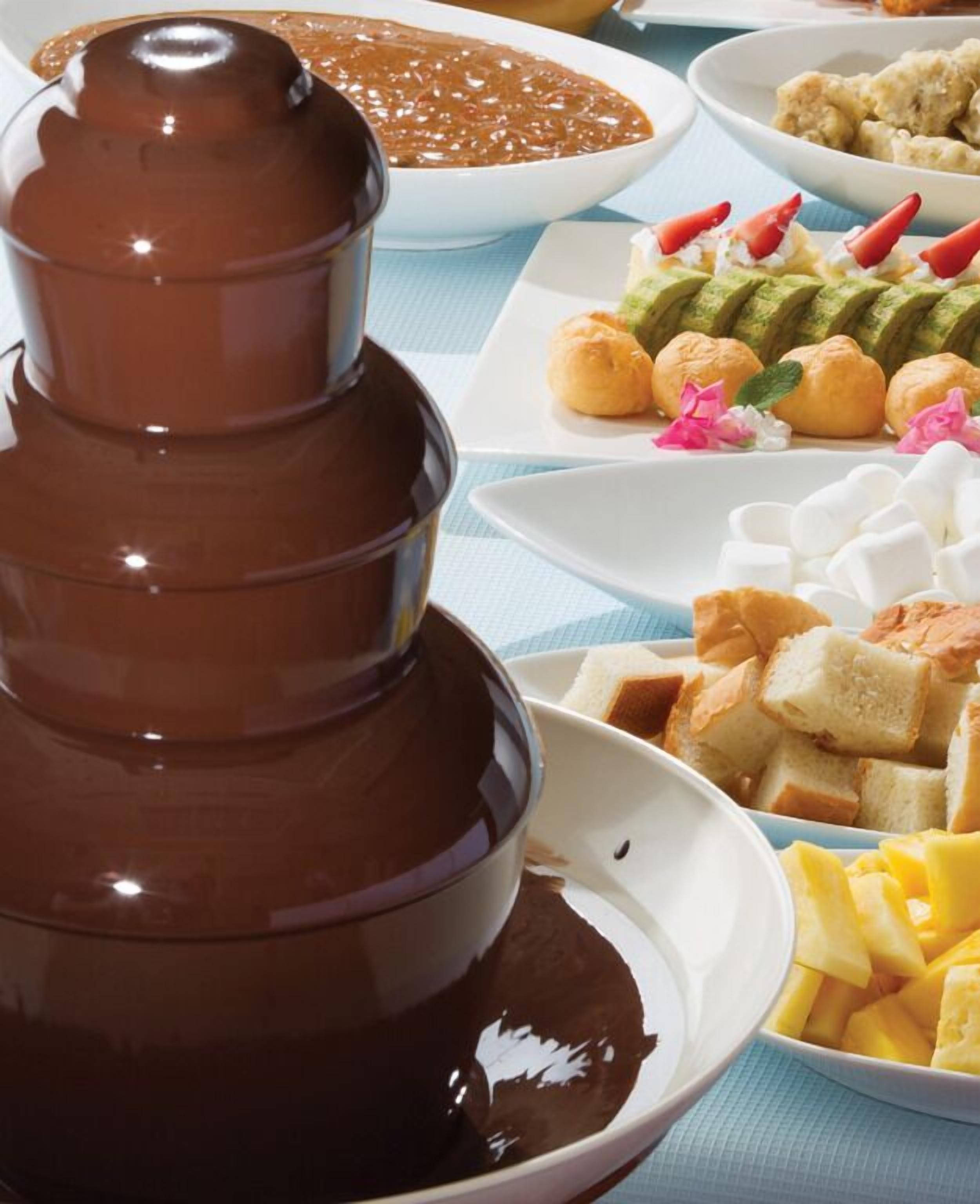 Una fuente de chocolate rodeada de diversos postres y aperitivos.