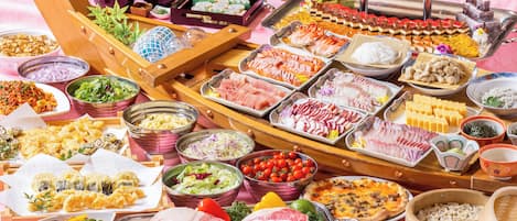 Ein Buffet mit verschiedenen Speisen, darunter Sushi, Fleisch und Gemüse.
