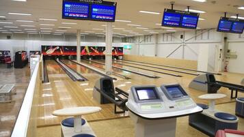 Bolera con múltiples carriles, sistema de devolución de pelotas y marcadores electrónicos.