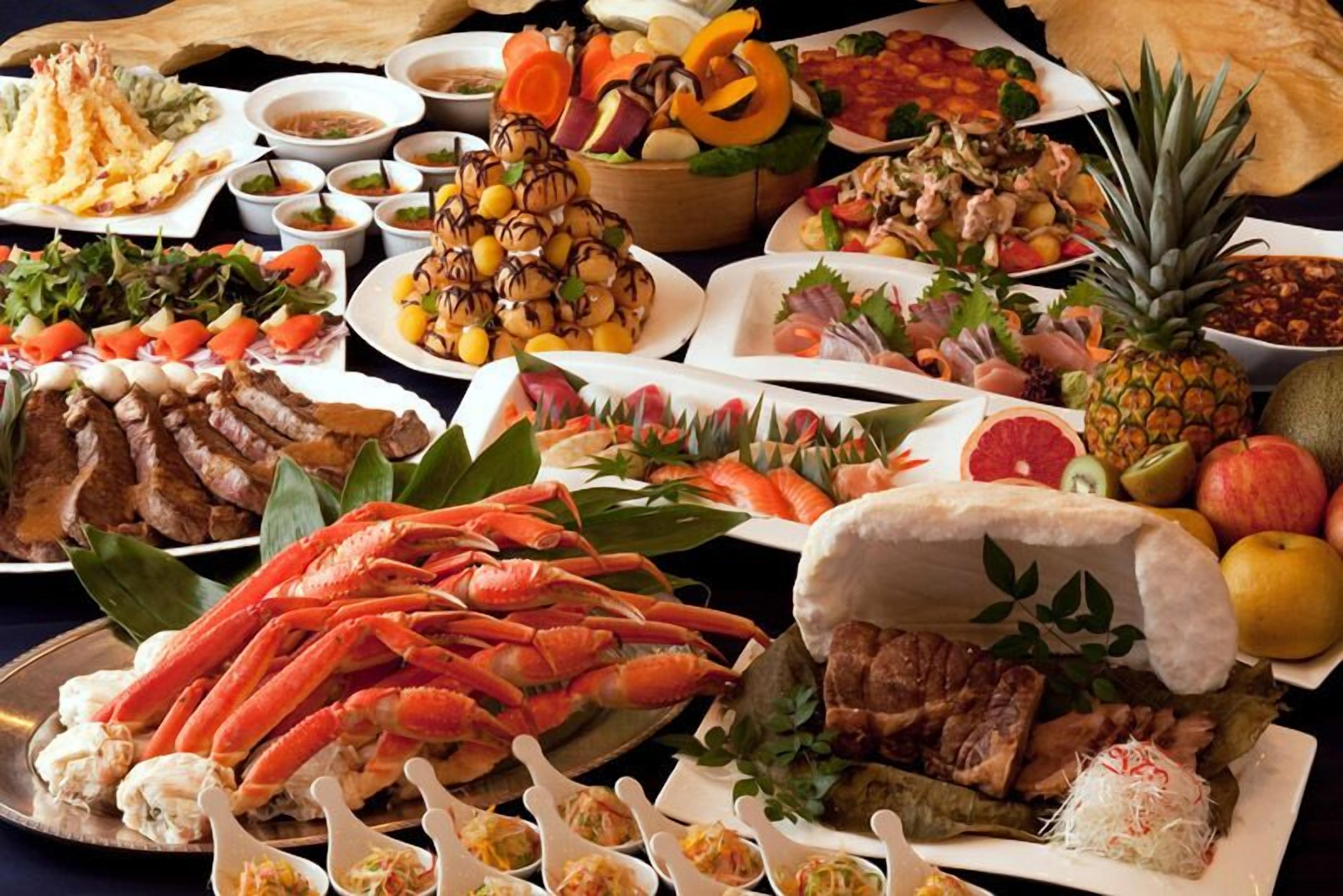 Diversos platos, incluyendo mariscos, ensaladas y carnes, dispuestos sobre una mesa.