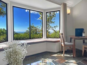 A room with large windows offering a scenic view of greenery and mountains.