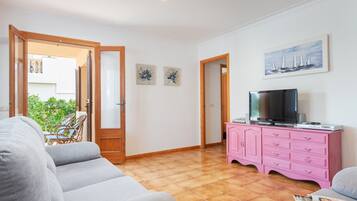 A living room with a sofa, a pink cabinet, and a television.
