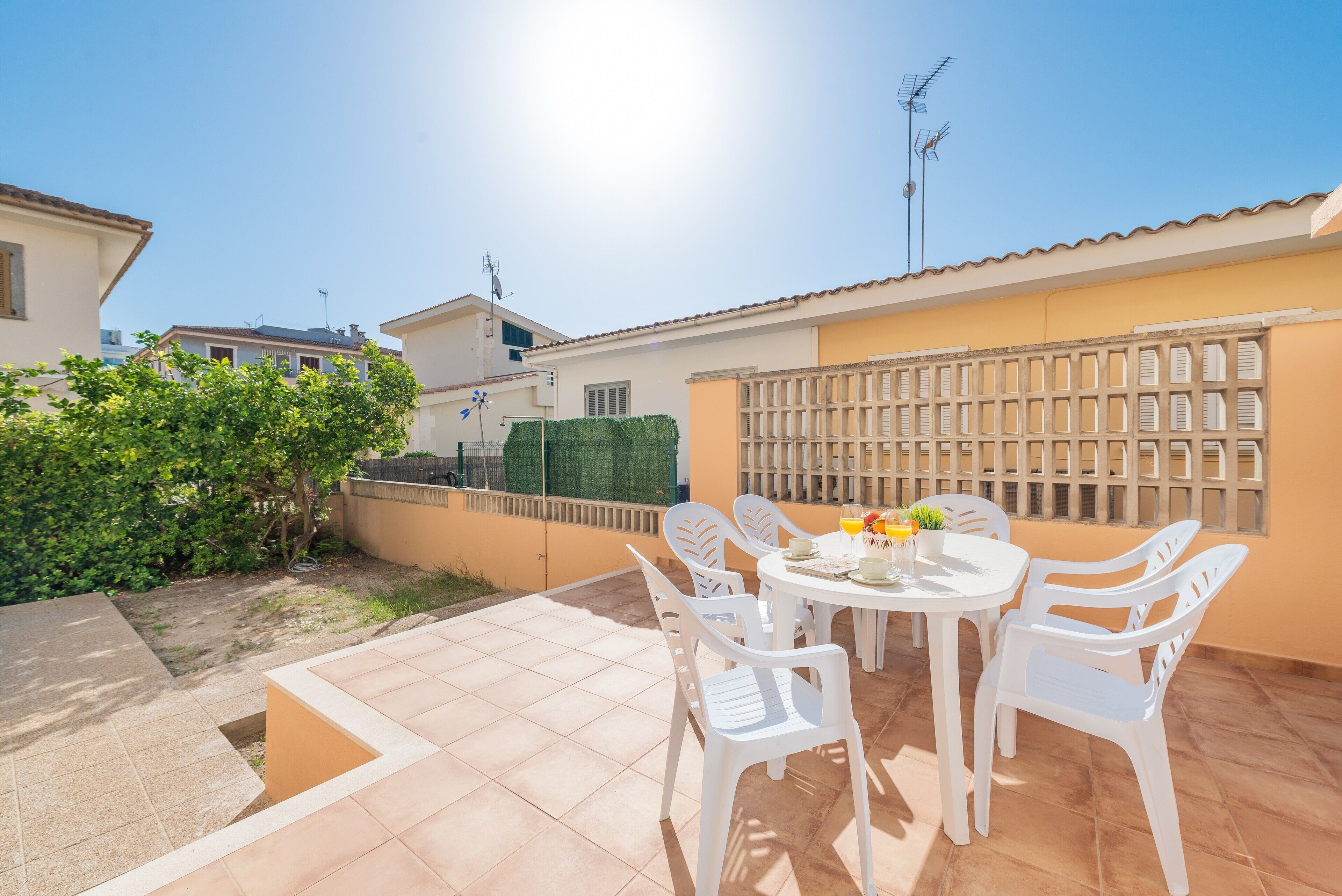 A patio with a table and chairs, surrounded by a low wall and a fence.