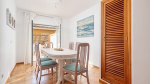 A dining area with a round table, six chairs, and a view of the outside through a glass door.