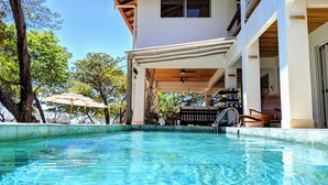 A pool area with a wooden deck, lounge chairs, and umbrellas.