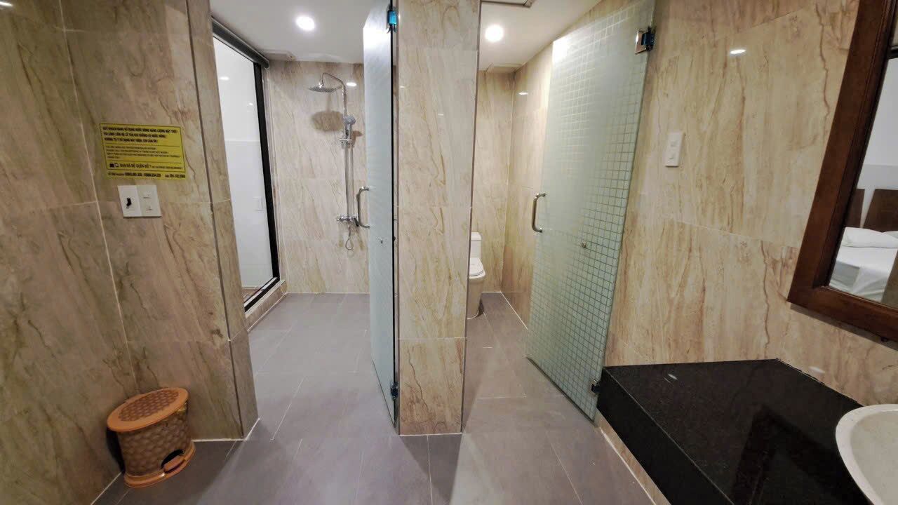 A modern bathroom with a glass shower enclosure, a toilet, and a sink area.