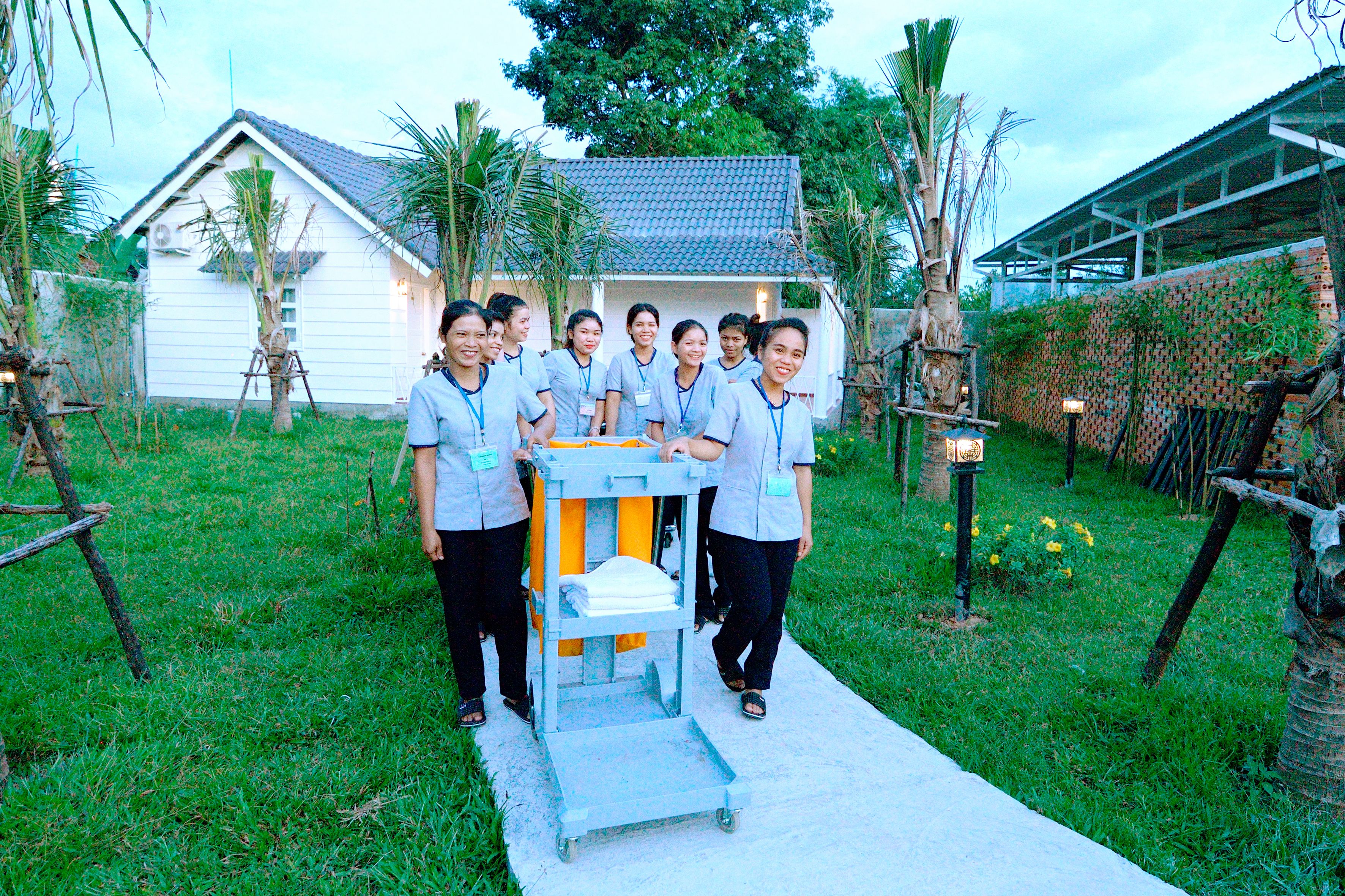 A group of people standing in a garden with a white building in the background.