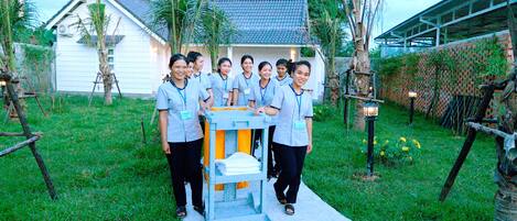 A group of people standing in a garden with a white building in the background.