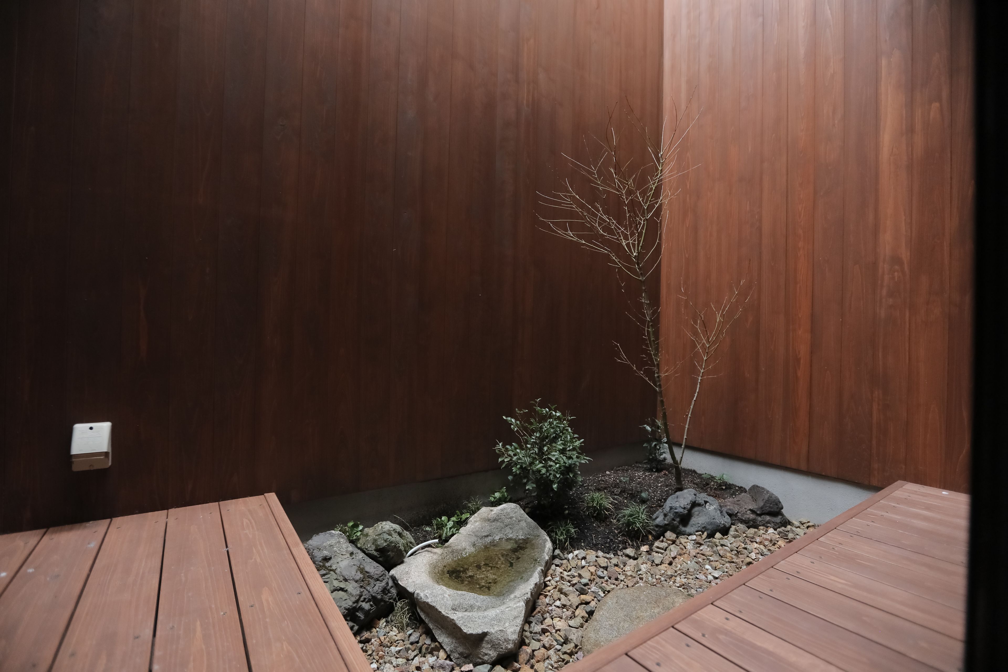 A wooden deck with a small rock garden and a bonsai tree.