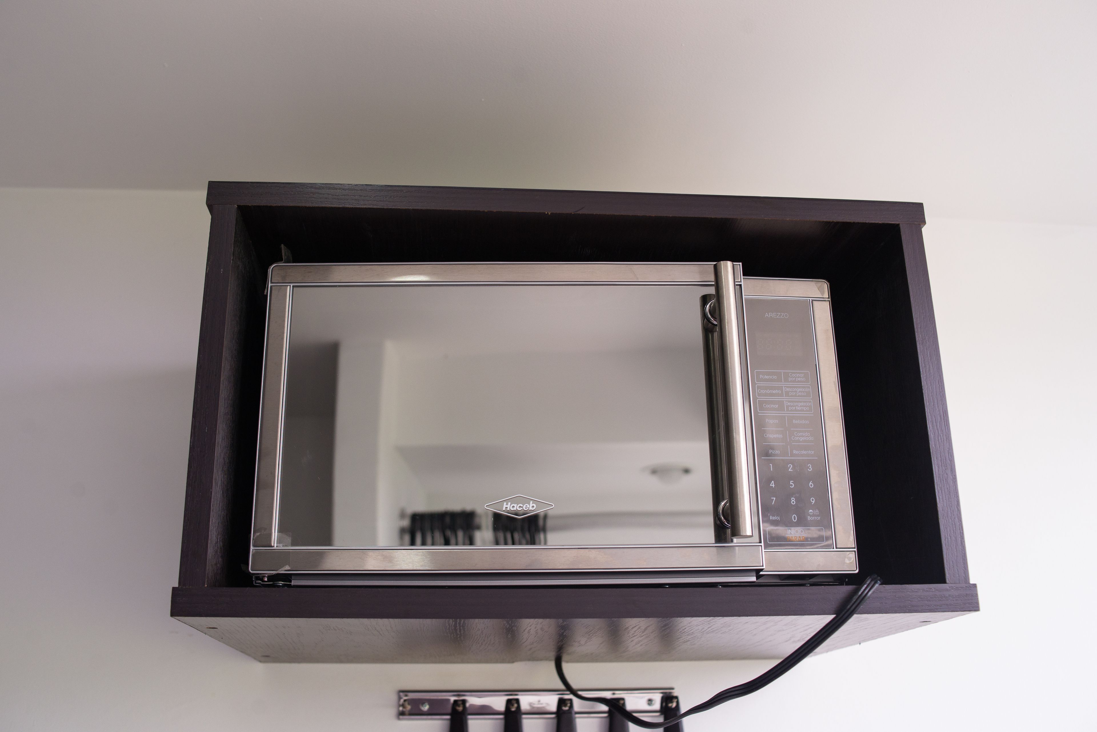 A microwave oven in a dark cabinet with a control panel on the right side.