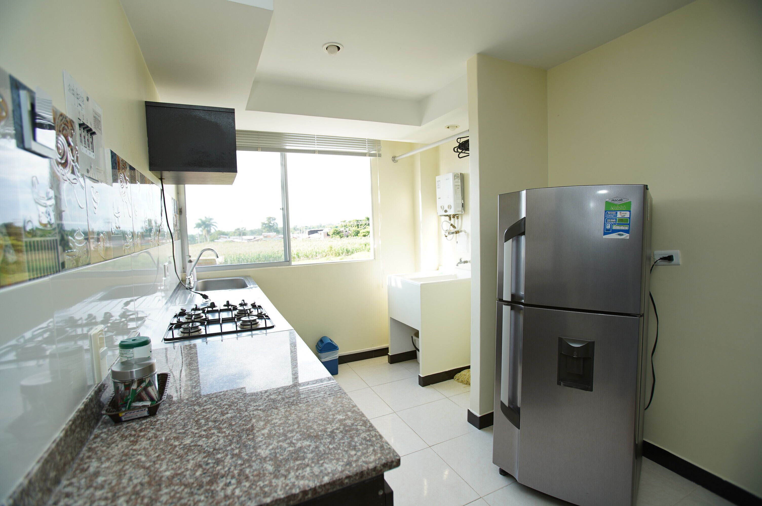 Una cocina con un refrigerador de acero inoxidable, una estufa a gas, un fregadero y una ventana con vistas al exterior.