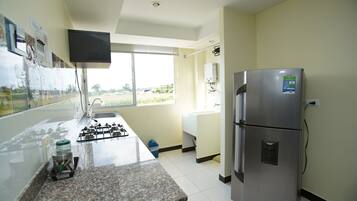 Una cocina con un refrigerador de acero inoxidable, una estufa a gas, un fregadero y una ventana con vistas al exterior.