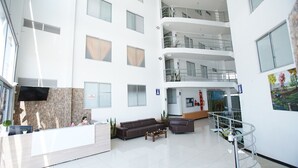 A modern hotel lobby with a reception desk, seating area, and a staircase leading to upper floors. - Guaduales del café 304 (Montenegro)