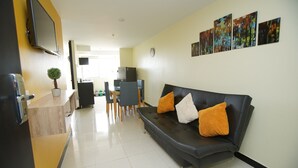 A modern living room with a black leather sofa, a wooden coffee table, and a flat-screen TV mounted on the wall. There are four framed artworks above the sofa and a small potted plant on the coffee table. - Guaduales del café 304 (Montenegro)