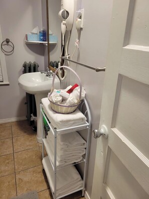 A bathroom with a sink, a hairdryer, a basket of towels, and a towel rack. - COZY HOME- Located on a quiet Worthy Street with a home in its own compound. (Springfield)