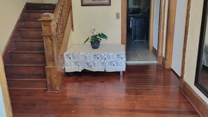 A wooden staircase with a white table and a potted plant in the hallway. - COZY HOME- Located on a quiet Worthy Street with a home in its own compound. (Springfield)
