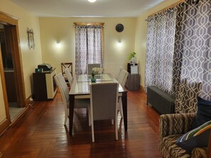 A dining area with a table and chairs, a clock on the wall, and patterned curtains. - COZY HOME- Located on a quiet Worthy Street with a home in its own compound. (Springfield)