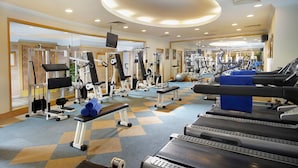 Un gimnasio con cintas de correr, máquinas de pesas y un espejo grande.