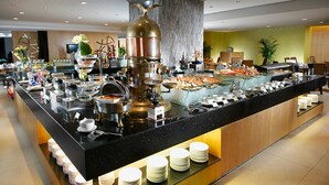 Montaje de bufé con diferentes estaciones de comida, una máquina de café y un gran centro de mesa decorativo.